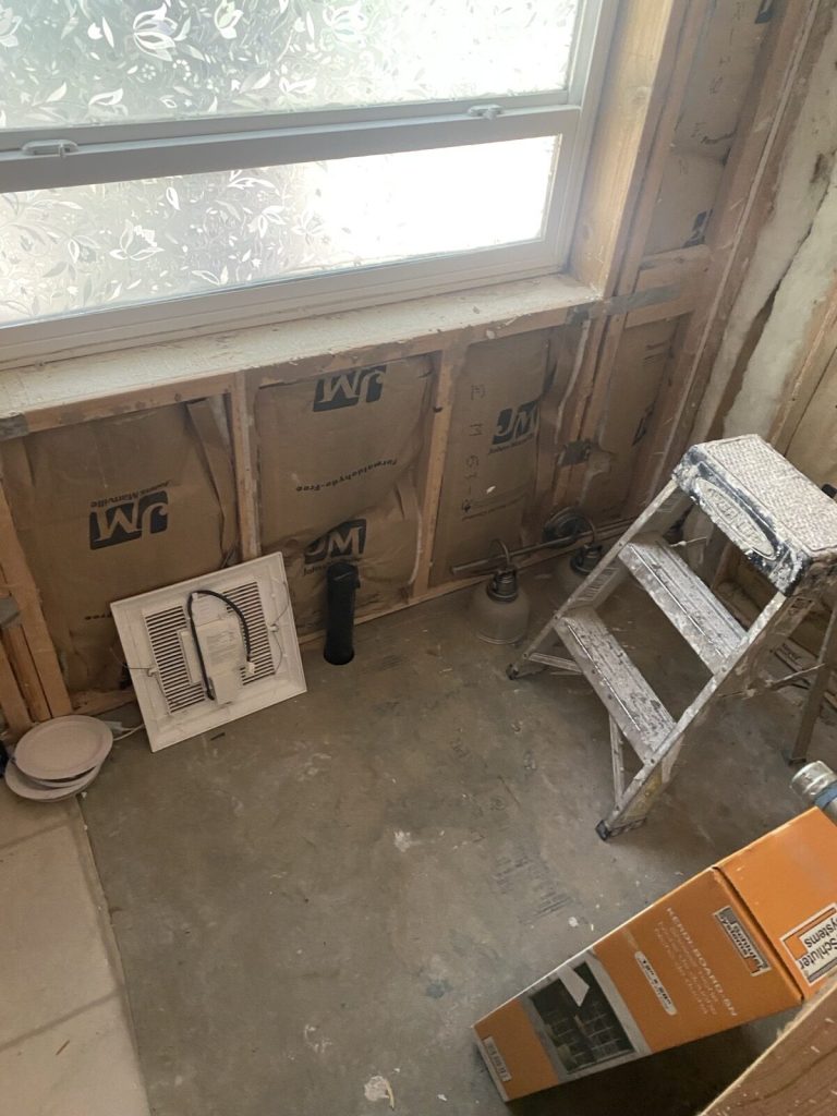 Old bathroom exhaust fan grille removed during demolition, with the wall opened to the studs